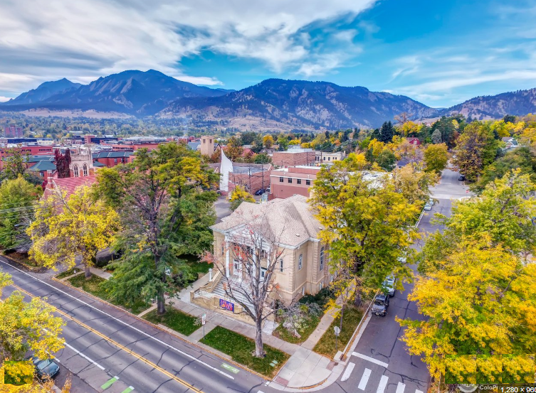 Whittier neighborhood in central Boulder, Colorado — aerial autumn view of historic architecture along tree-lined streets with the Flatirons rising in the background
