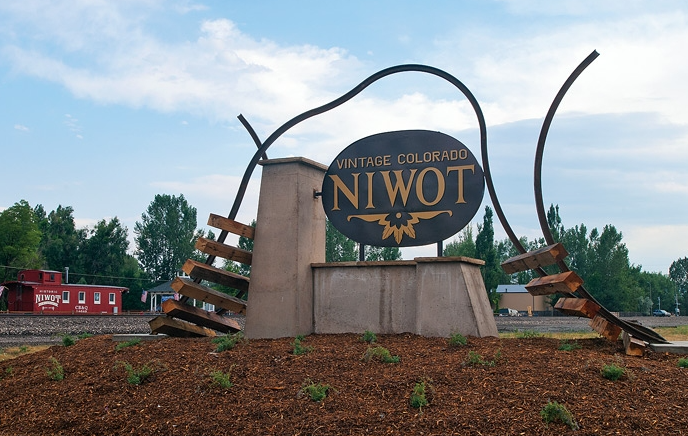 Niwot real estate — Vintage Colorado Niwot welcome sign monument with red railroad caboose in background, marking the entrance to the historic town